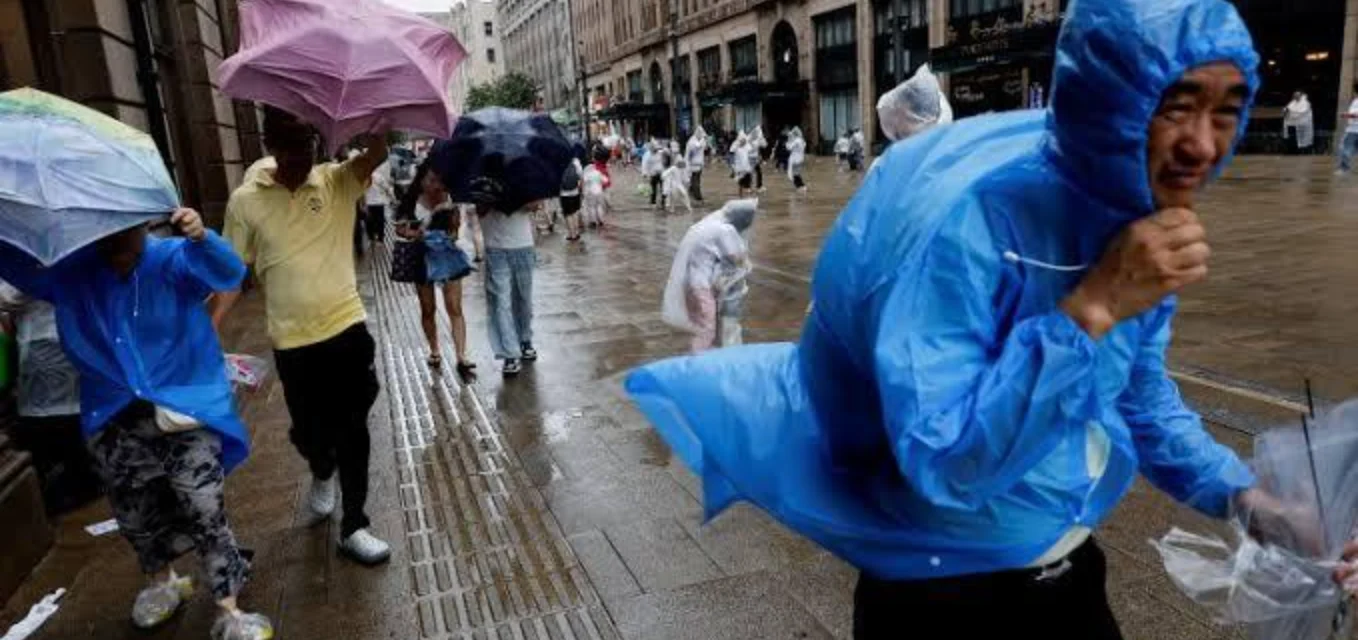 People in raincoats and umbrellas walk through flooded streets as a typhoon hits coastal China today.