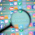 Magnifying glass over social media icons, highlighting concerns about youth online safety and harms.