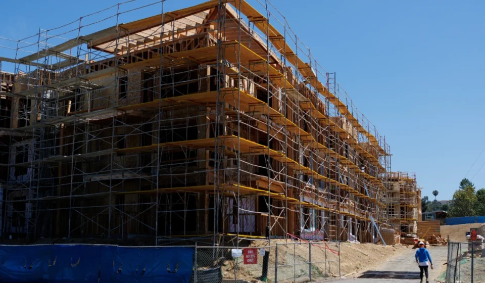 U.S. Remodeling Expenditure Drops as Construction Hiring Rises Construction workers walk past a multi story residential building under construction with scaffolding.