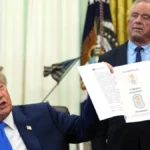 Donald Trump holds a document on childhood vaccines as Robert F. Kennedy Jr. stands behind him here.