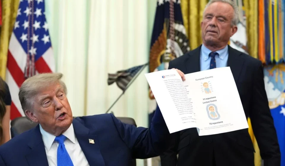 Donald Trump holds a document on childhood vaccines as Robert F. Kennedy Jr. stands behind him here.