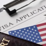US visa application form with American flag, passport, pen, papers showing journalist visa vetting.