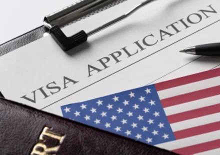 US visa application form with American flag, passport, pen, papers showing journalist visa vetting.