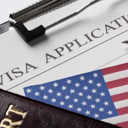 US visa application form with American flag, passport, pen, papers showing journalist visa vetting.