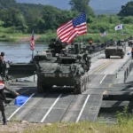 US and South Korean troops conduct a military exercise with armored vehicles crossing a river.