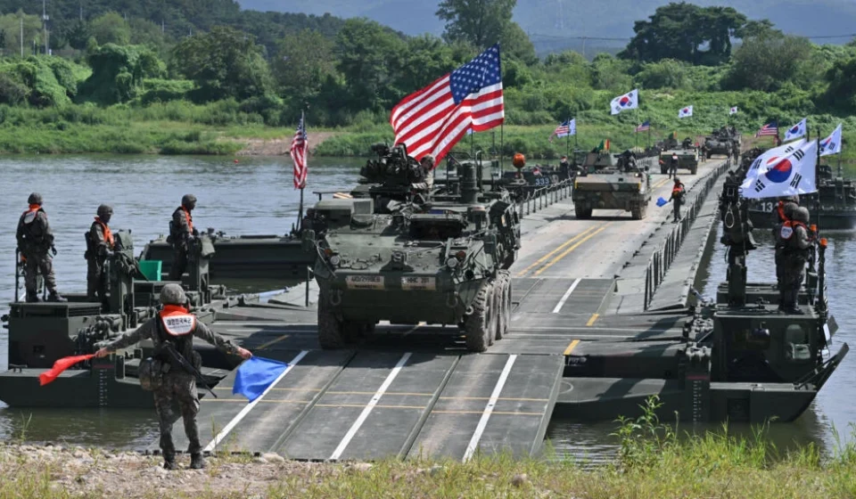 US and South Korean troops conduct a military exercise with armored vehicles crossing a river.