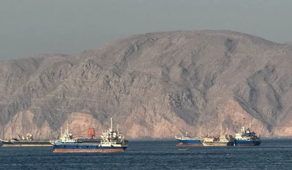 US and Iran Begin Oman-Mediated Talks Over Maritime Transit Cargo ships sail through the Strait of Hormuz with rocky coastline during US Iran maritime talks underway.