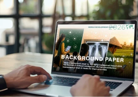Laptop displays World Bank 2026 WDR background paper with education, medical and farming scenes.